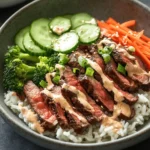 Embark on a culinary journey to Korea with this delightful recipe for Korean BBQ Steak Rice Bowls, topped with a zesty spicy cream sauce. This dish marries savory marinated steak with fresh vegetables and creamy sauce, offering a harmonious balance of flavors and textures. Perfect for a weeknight dinner or a gathering with friends, these rice bowls are easy to prepare and can be customized to suit your taste. In this article, we’ll explore each component of the recipe, providing step-by-step instructions and insights into the ingredients that make this dish special.
